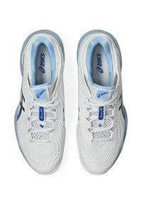 Baskets blanches avec un dessus en maille respirante, accents bleu clair, logo noir et une conception de semelle robuste adaptée aux sports de terrain.