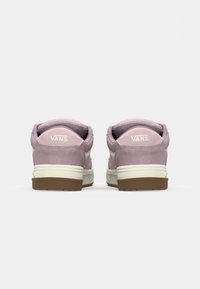Vans tenised kerge roosa suede pealisosa, valged aktsendid ja pruun kummitald; funktsioonid pehmendatud kaelus ja logo kandadel.
