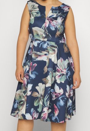 Ærmeløs mørkeblå kjole med store pastelfarvede blomsterprint og en let V-udskæring, båret af en person vist fra nakke til knæ.