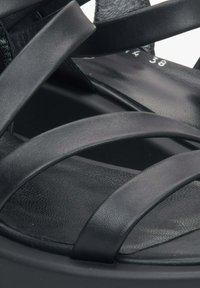 Czarne skórzane sandały mają wiele nachodzących na siebie pasków, teksturowaną wkładkę oraz zaokrągloną podeszwę podnoszącą stabilność. Rozmiar oznaczony jako 38.