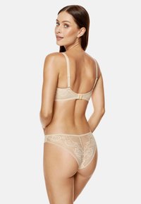 Koronkowy stanik i dopasowane majtki w kolorze nude, zdobione kwiatowymi wzorami, z regulowanymi ramiączkami oraz zapięciem na haczyk i oczko z tyłu.