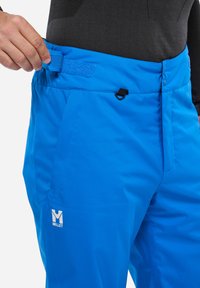 Blaue Outdoor-Hosen aus leichtem Material, mit einem Klettverschlussbund und einem Reißverschluss. Logo auf dem linken Oberschenkel angezeigt.