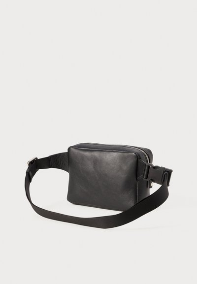 Sac bandoulière en cuir noir avec une texture lisse, forme rectangulaire, fermeture éclair et une bandoulière ajustable. Présente des accents en matériel durable.