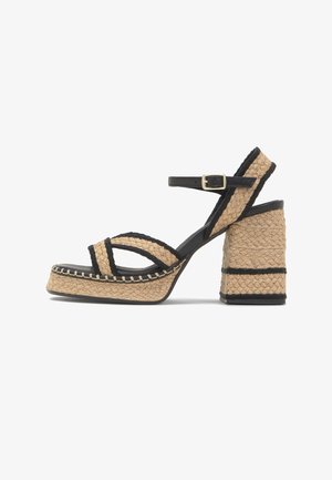 Platformsandaal met gevlochten hiel en bandjes van natuurlijke vezels, zwarte randafwerking, enkelgesp en stevige blokhak.