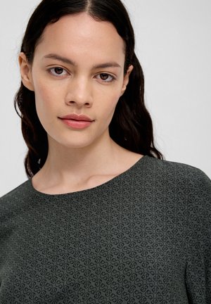 Groene top met een subtiel doorlopend patroon van in elkaar grijpende vormen, ronde halslijn en een gladde textuur.
