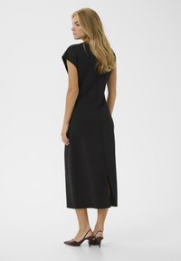 Melna midi kleita ar piedurknēm, pieguļošs dizains, sānu izgriezums, gluda auduma un slēpts rāvējslēdzis aizmugurē. Valkājama ar bordo augstpapēžu kurpēm.