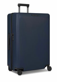 Maleta rígida azul marino con acabado texturizado, asa telescópica, cierre con cremallera y cuatro ruedas negras para facilitar su movilidad.