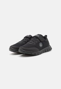 Baskets noires de sport avec une tige en mesh respirant, semelle en caoutchouc et lacets élastiques. Dotées d'une sangle Velcro et d'un logo sur le côté.