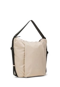 Bolso de hombro rectangular beige con correas negras ajustables y un logo sutil de "DEHA" en el frente, colocado de pie sobre un fondo blanco.