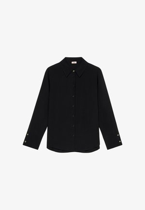 Blouse noire à manches longues avec un col pointu, fermeture à boutons sur le devant et accents en boutons dorés sur les poignets. Tissu lisse, coupe ajustée.