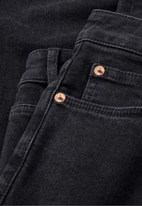 Schwarze Jeans aus Denim mit einer weichen Textur, ausgestattet mit Kupfennieten, doppelt genähten Nähten und einer Vorderasche.