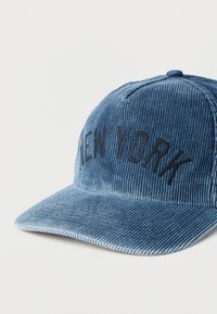 Μπλε καπέλο από κορντουρό με κεντημένο το "NEW YORK" σε σκούρο κείμενο, καμπυλωτό γείσο και υφή υφάσματος.