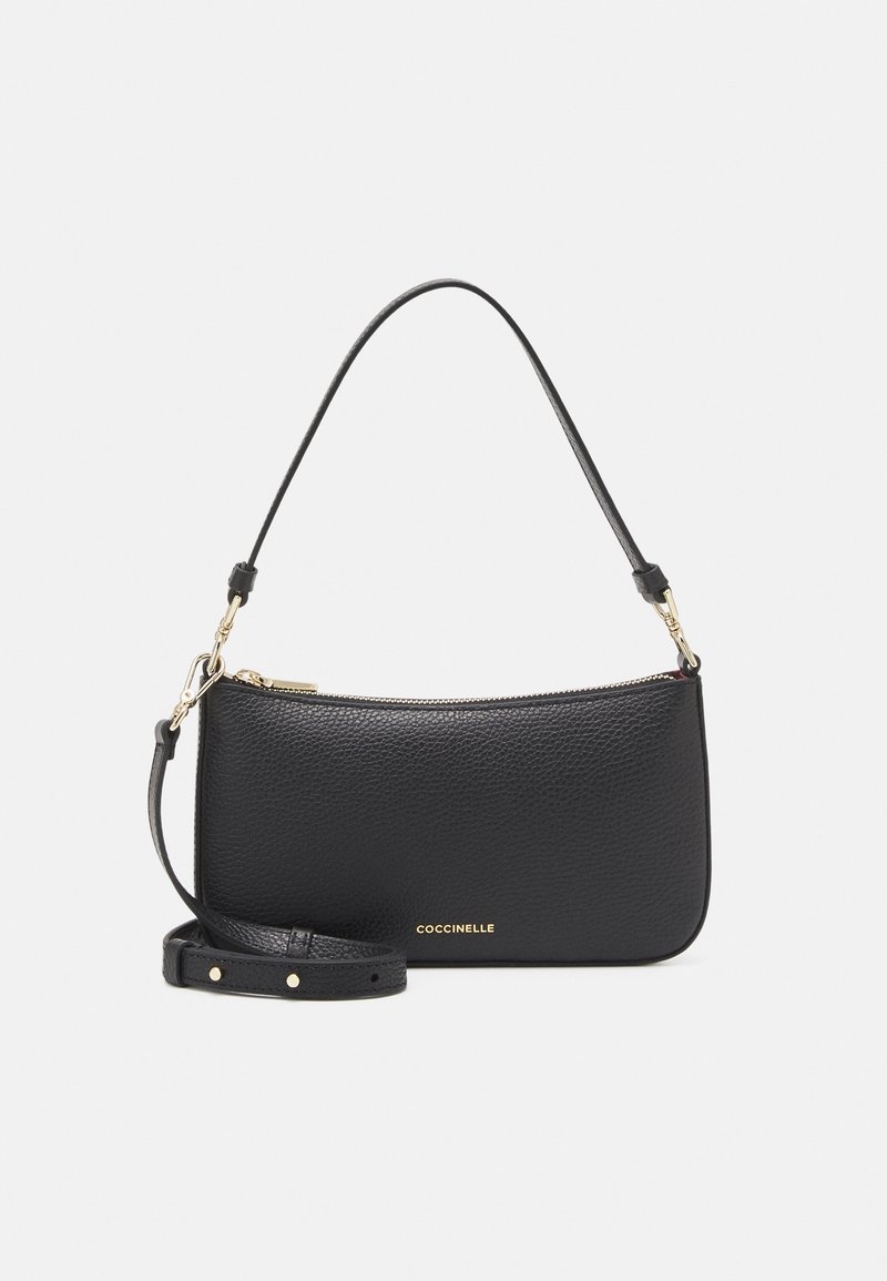 Sac à main en cuir noir texturé avec fermeture éclair dorée, bandoulière détachable et poignée courte, marqué avec "COCCINELLE" en lettres dorées.
