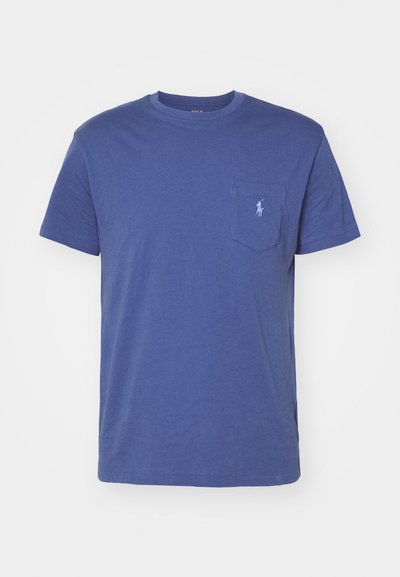 T-shirt de algodão azul com colarinho redondo, mangas curtas e um bolso frontal com um pequeno logo bordado. Textura suave, design simples.