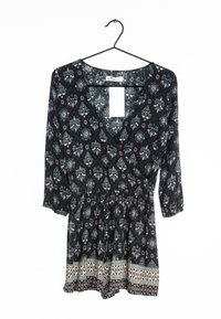 Černý květinový overal s V-výstřihem, tříčtvrtečními rukávy, elastickým pasem a dekorativním lemem s geometrickými vzory na spodním okraji.