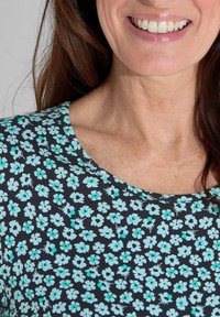 Haut noir à manches courtes avec un motif floral en teal et blanc, un col rond et un tissu doux et texturé.