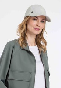 Helle graue Kappe mit strukturiertem Design und kleinem Logo, kombiniert mit einer grünen Bomberjacke mit Fronttaschen und glatter Textur.