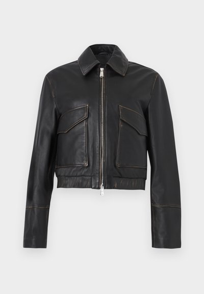 Μαύρο δερμάτινο μπουφάν με μπροστινό φερμουάρ, δύο τσέπες με καπάκι, γιακά και μακριά μανίκια, εμφανιζόμενο σε απλό ανοιχτό φόντο.