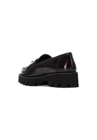 Zapatos negros de charol tipo slip-on con una suela de goma negra gruesa y acentos texturizados, que presentan un diseño clásico y un tacón bajo.