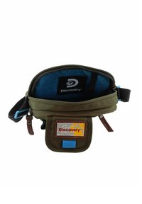 Borsa compatta verde oliva con interno a motivi blu, chiusura con zip, tasca frontale e logo a patch. Presenta dettagli marroni e tracolla regolabile.