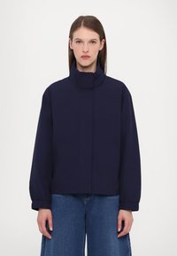 Navy blue bomber jacket with a high collar, dropped shoulders, and elastic cuffs. Features side pockets and a smooth, matte texture.