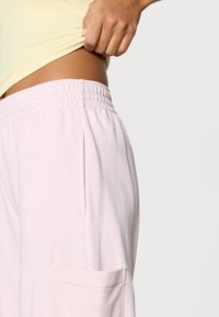 Απαλά ροζ βαμβακερά παντελόνια φόρμας με ελαστική μέση, με πλαϊνές τσέπες και άνετη γραμμή. Η υφή τους είναι απαλή και λεία.