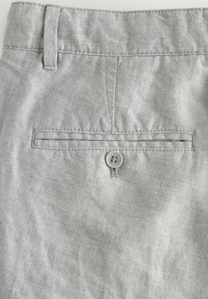 Pantaloni in denim grigio che mostrano una trama liscia, una tasca posteriore con bottone e passanti per cintura lungo la vita.