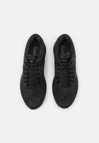 Ténis desportivos pretos com um upper em malha, bico arredondado e atacadores. Possui um logótipo discreto e uma sola texturizada para melhor aderência.