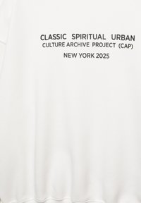 Felpa bianca con audace testo nero: "CLASSIC SPIRITUAL URBAN CULTURE ARCHIVE PROJECT (CAP) NEW YORK 2025." Tessuto morbido, vestibilità rilassata.