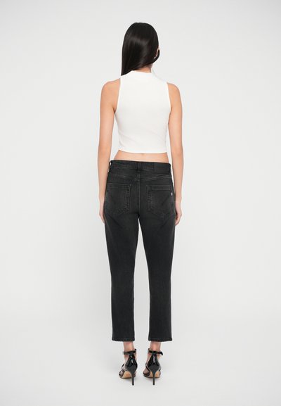 Top corto blanco combinado con jeans de mezclilla negros. Los jeans tienen un corte recto, bolsillos traseros y un ligero desgaste. Tacones altos negros completan el atuendo.