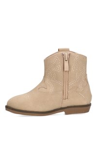 Botas de ante beige hasta el tobillo con cremallera lateral, que presentan costuras decorativas en blanco y una suela marrón baja. Diseño de puntera ligeramente redondeada.