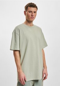 Camiseta oversized de color verde claro en una suave mezcla de algodón, con cuello redondo y mangas cortas, exhibida en un modelo con un fondo neutro.
