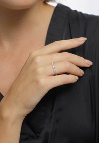 Silver ring med rektangulära och kvadratiska ädelstenar, inramad i en elegant design. Visad för hand med neutral nagellack mot en svart textil.
