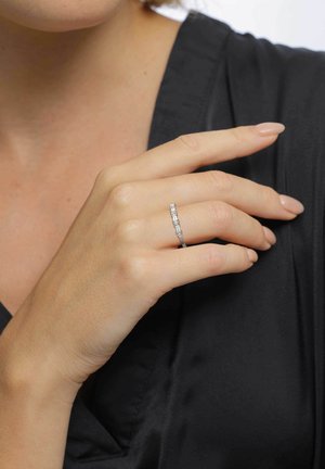 Silver ring med rektangulära och kvadratiska ädelstenar, inramad i en elegant design. Visad för hand med neutral nagellack mot en svart textil.