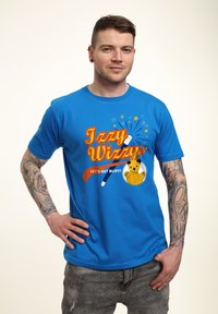 Modrá bavlněná tričko s grafikou "Izzy Wizzy" se hvězdami, hůlkou a žlutou postavičkou. Krátké rukávy, kulatý výstřih, volný střih.