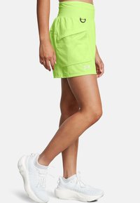 Pantalones cortos deportivos en verde lima con una amplia cinturilla elástica, bolsillo frontal y el logo de Under Armour en blanco en el dobladillo inferior.