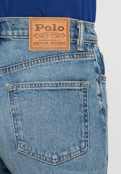 Ljustblå denimjeans med texturerad yta, med en brun läderpatch med "Polo Ralph Lauren"-logotyp vid midjan.