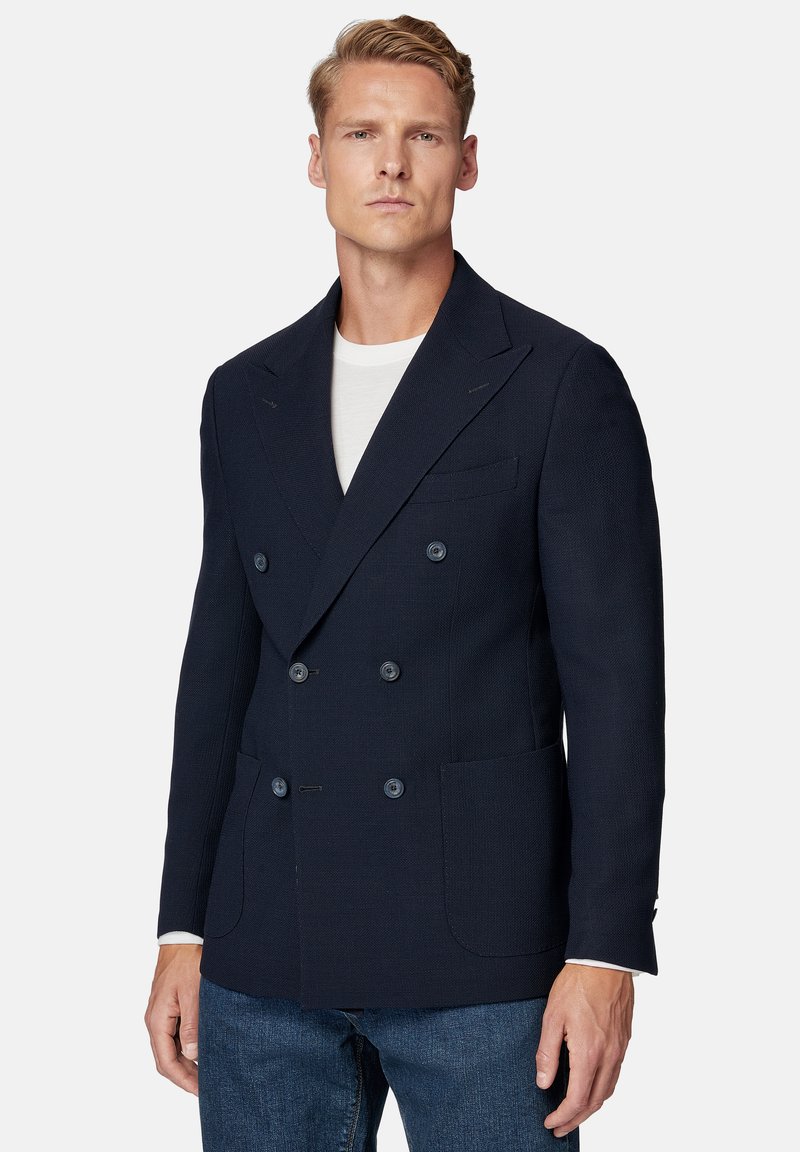 Granatowy marynarka dwurzędowa wykonana z fakturowanej tkaniny, z klapami, dwoma przednimi kieszeniami i sześcioma guzikami. Luźny fason z białym T-shirtem.
