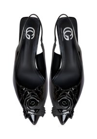 Zwarte slingback hakken van lakleer met puntige neuzen en grote decoratieve zwarte rozenversieringen op elke schoen.