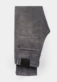 Szare dżinsy w charakterystycznym kroju, z tylną kieszenią o haftowanym wzorze i czarną metką marki na pasku.