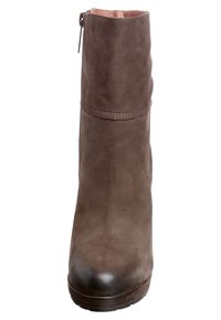 Botte de cheville en cuir marron avec une texture lisse, bout arrondi et fermeture éclair sur le côté. Présente une légère plateforme pour un peu plus de hauteur.