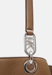 Bandoulière de sac à main en cuir marron avec surface texturée, accents métalliques argentés comprenant un clip géométrique et une attache en anneau circulaire.