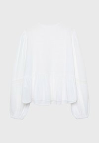 Weiße Bluse mit langen Ärmeln, die einen Peplum-Saum und zarte Spitzenverzierungen im Bereich des Oberkörpers aufweist, aus leichtem Stoff gefertigt.
