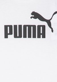 Biela bavlnená tričko s veľkým čiernym logom "PUMA" a skákacím čiernym puman na vrchu textu. Hladká textúra, neformálny dizajn.
