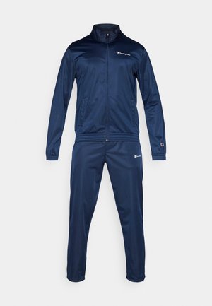 Chándal de color marino hecho de una tela suave, que incluye una chaqueta con cremallera y cuello alzado, y pantalones a juego. Presenta logotipos en el pecho y la pierna.