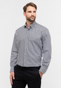 Camicia a maniche lunghe da uomo con sottili righe nere e bianche, colletto button-down, taschino sul petto e polsini a righe in contrasto.