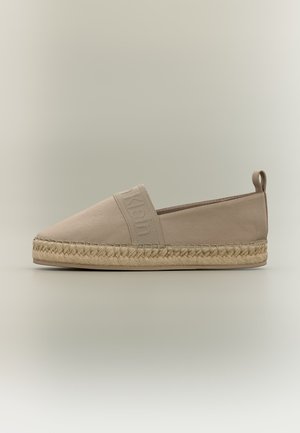 Beige slip-on espadrille med flettet jutesåle, elastisk bånd over toppen med preget merkenavn, og stoffløkke bak på hælen.