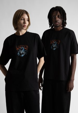 Schwarze Baumwoll-T-Shirts sind mit einem Grafikdesign auf der Vorderseite versehen, das einen Skorpion und das Wort "WASTED" zeigt. Die T-Shirts haben kurze Ärmel und einen lockeren Schnitt.