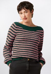 Multicolored knitted sweater featuring a geometric pattern in pink, green, and cream. Oversized green collar and cuffs, with ribbed texture.