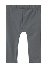 Graue Leggings aus weichem, dehnbarem Material. Sie verfügen über einen elastischen Bund und eine gewellte Saumverarbeitung an den Knöcheln.